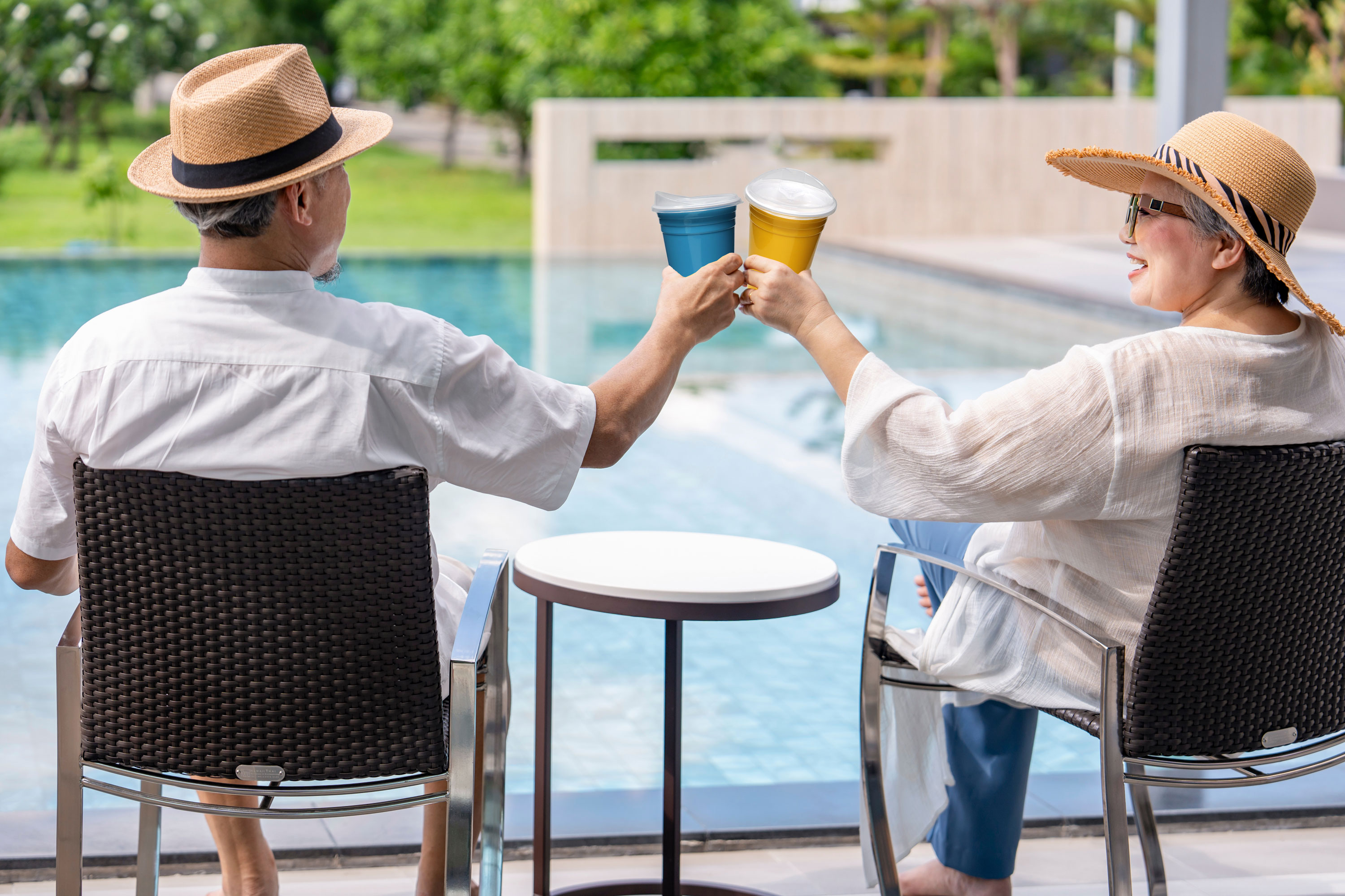Older couple enjoying a drink poolside.
